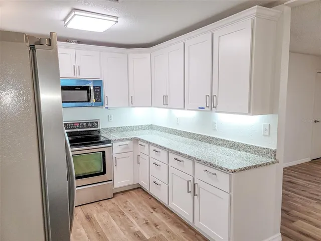 a kitchen with granite countertop a stove sink and refrigerator