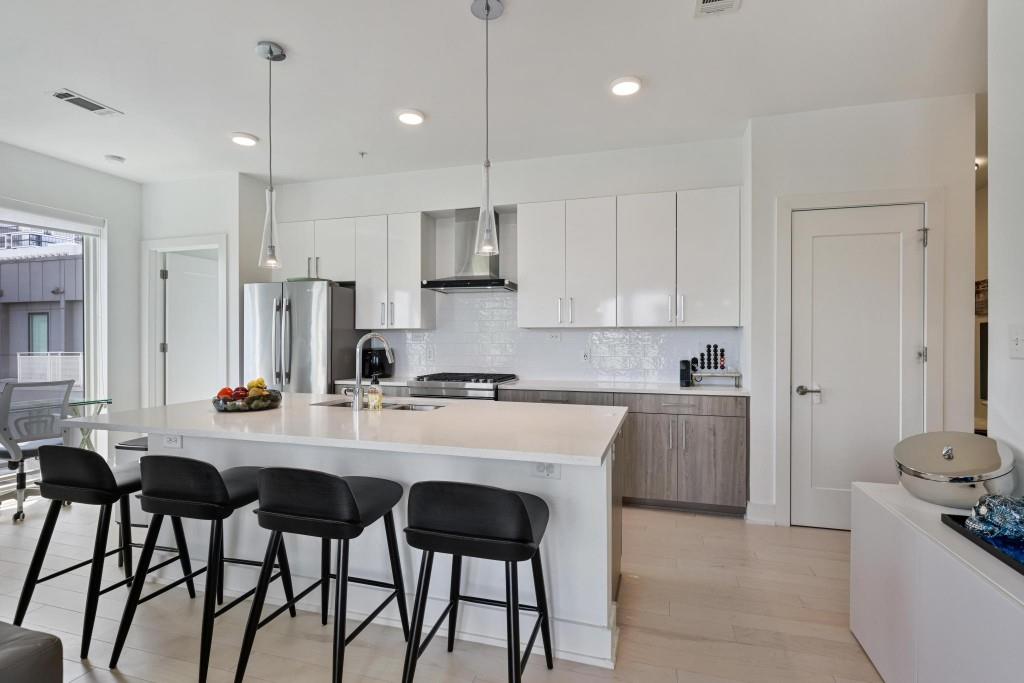 775 Juniper Street Northeast, Unit 602 Atlanta, GA 30308 - Photo 12 of 40 a kitchen with stainless steel appliances granite countertop a sink a stove a refrigerator and island with wooden floor