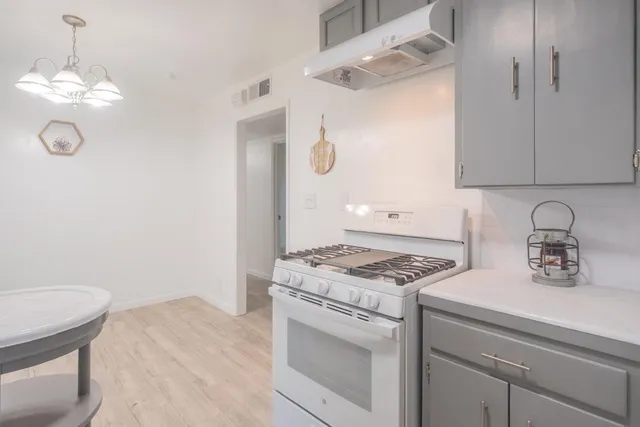 a kitchen with a stove cabinets and wooden floor