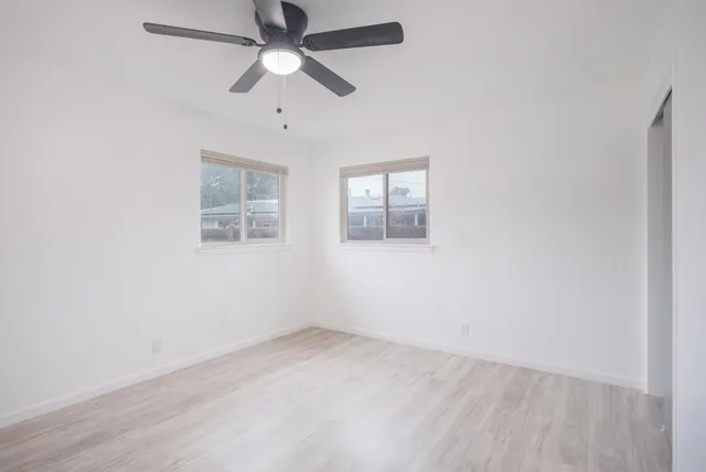 an empty room with a window and ceiling fan