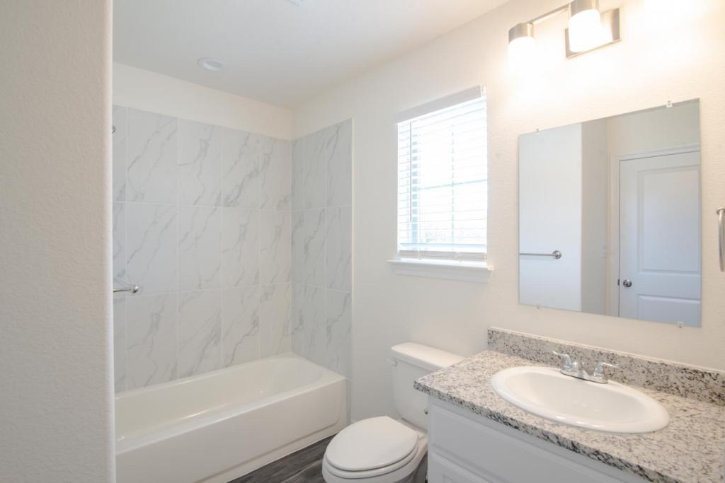 1516 Kennedy Street, Unit B Bonham, TX 75418 - Photo 8 of 11 a bathroom with a granite countertop sink toilet tub and shower