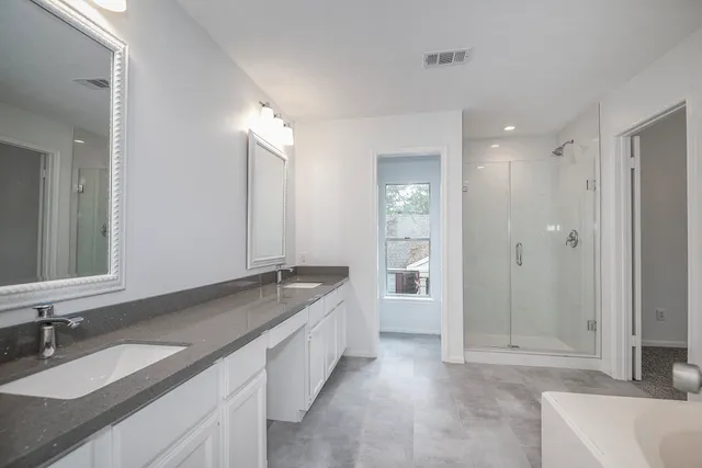 a spacious bathroom with a granite countertop tub sink shower and mirror