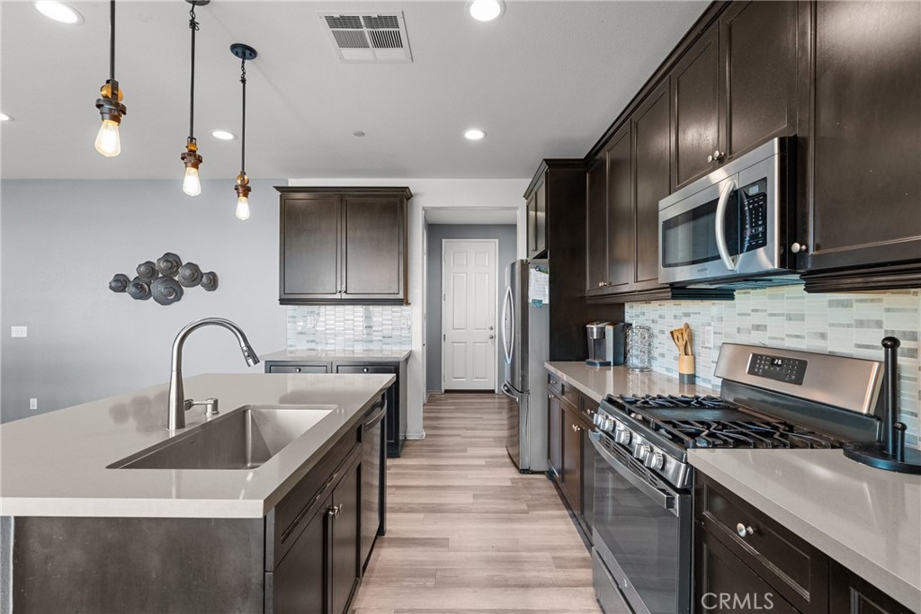 6949 Beale Road Palmdale, CA 93552 - Photo 9 of 32 a kitchen with stainless steel appliances a sink stove and cabinets