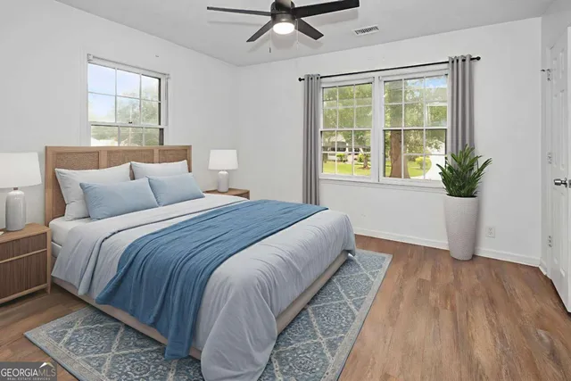 a bedroom with a large bed windows and wooden floor