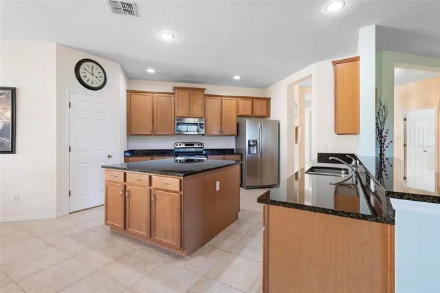 a kitchen with stainless steel appliances granite countertop a sink a stove a refrigerator a washer and dryer with a window