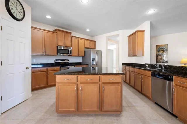 a large kitchen with stainless steel appliances granite countertop a stove a sink and a microwave