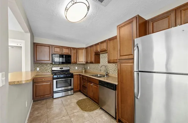 a kitchen with stainless steel appliances granite countertop a refrigerator sink stove and oven