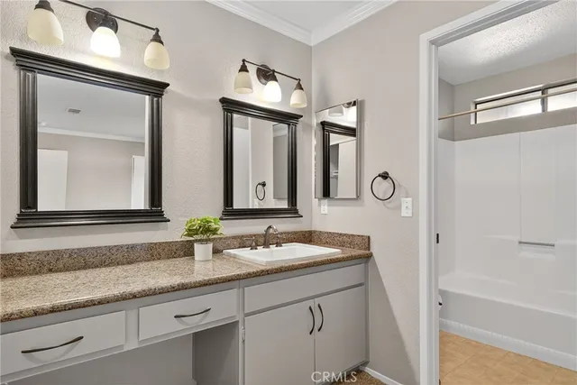 a bathroom with a granite countertop double vanity sink and a mirror