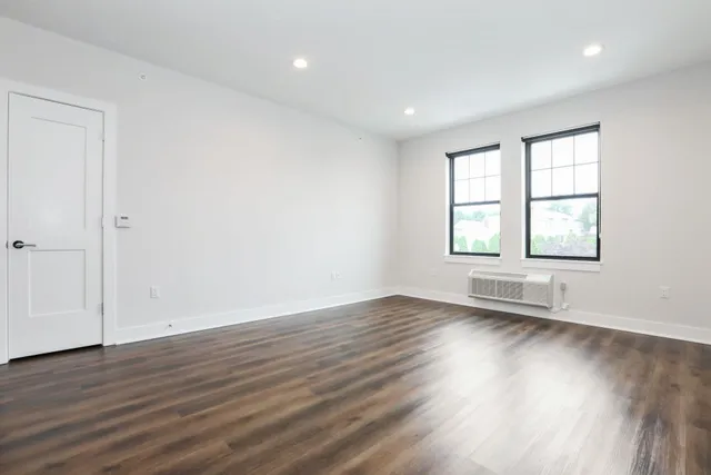 an empty room with wooden floor and windows