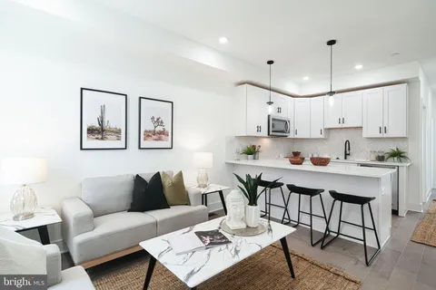 a living room with stainless steel appliances kitchen island a table and chair