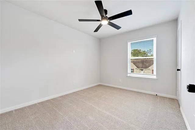 an empty room with a window and a fan