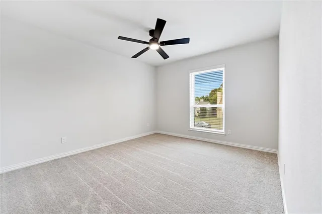 an empty room with ceiling fan and window