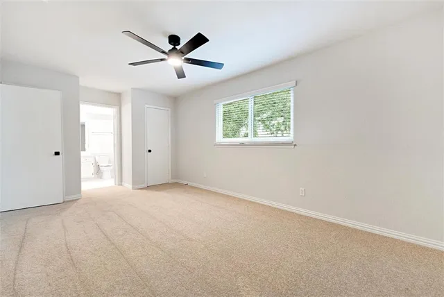 an empty room with window and ceiling fan