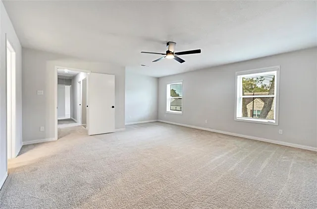 an empty room with windows and ceiling fan