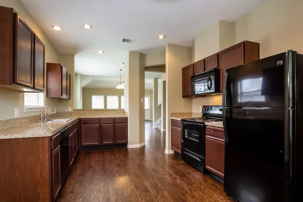a kitchen with stainless steel appliances kitchen island granite countertop a stove a sink and a refrigerator