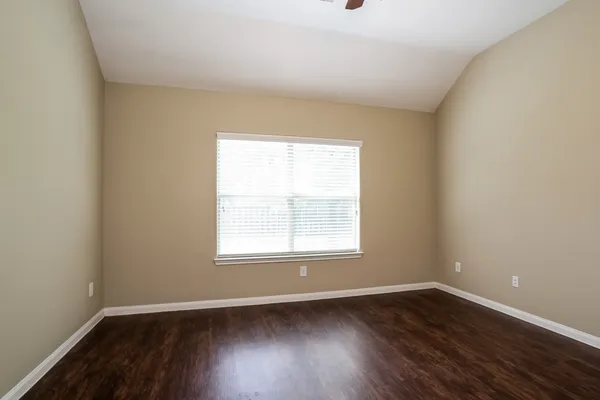 an empty room with wooden floor and window