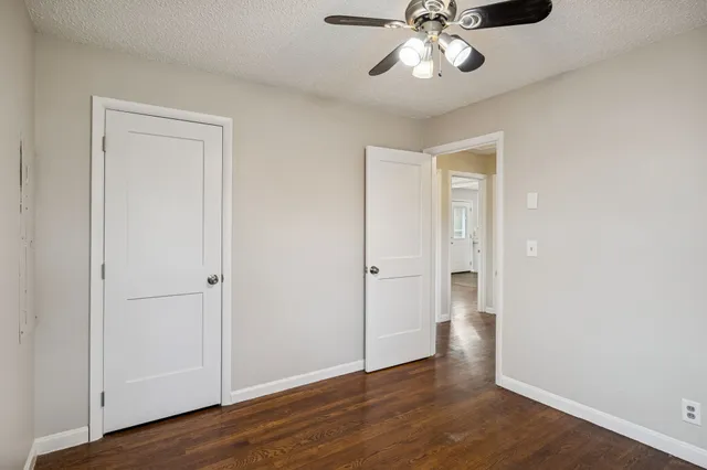 an empty room with wooden floor closet and windows