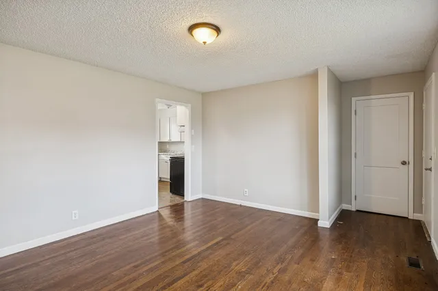 a view of empty room with wooden floor and window