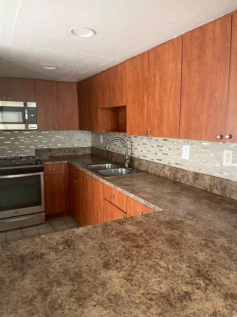 10090 Northwest 80th Court, Unit 1340 Hialeah Gardens, FL 33016 - Photo 9 of 17 a kitchen with stainless steel appliances granite countertop a stove a sink and a microwave