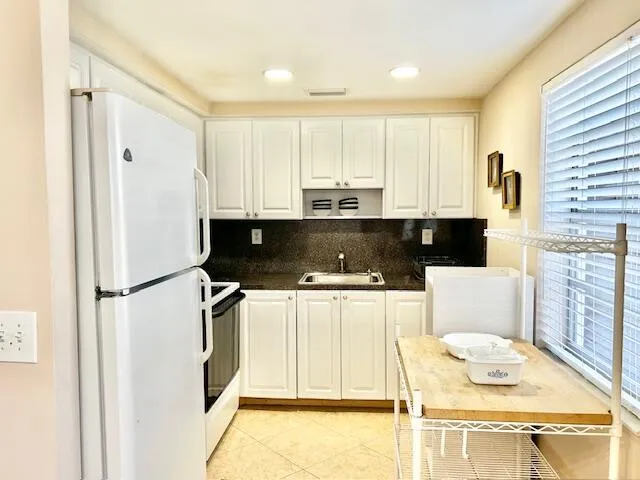 a kitchen with stainless steel appliances a refrigerator sink and white cabinets