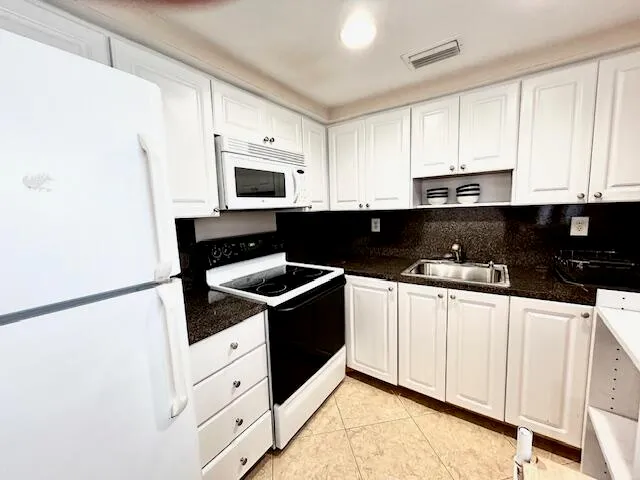 a kitchen with granite countertop white cabinets sink and stainless steel appliances
