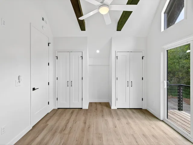 an empty room with wooden floor a ceiling fan and windows