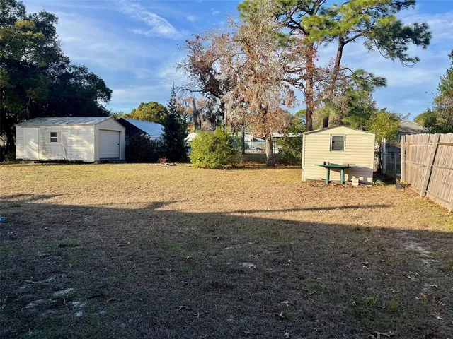 a view of a white house with a yard and large trees