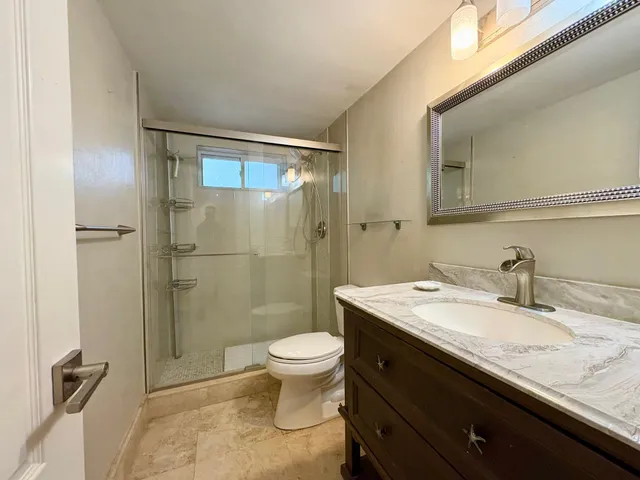 a bathroom with a granite countertop sink toilet a mirror and shower