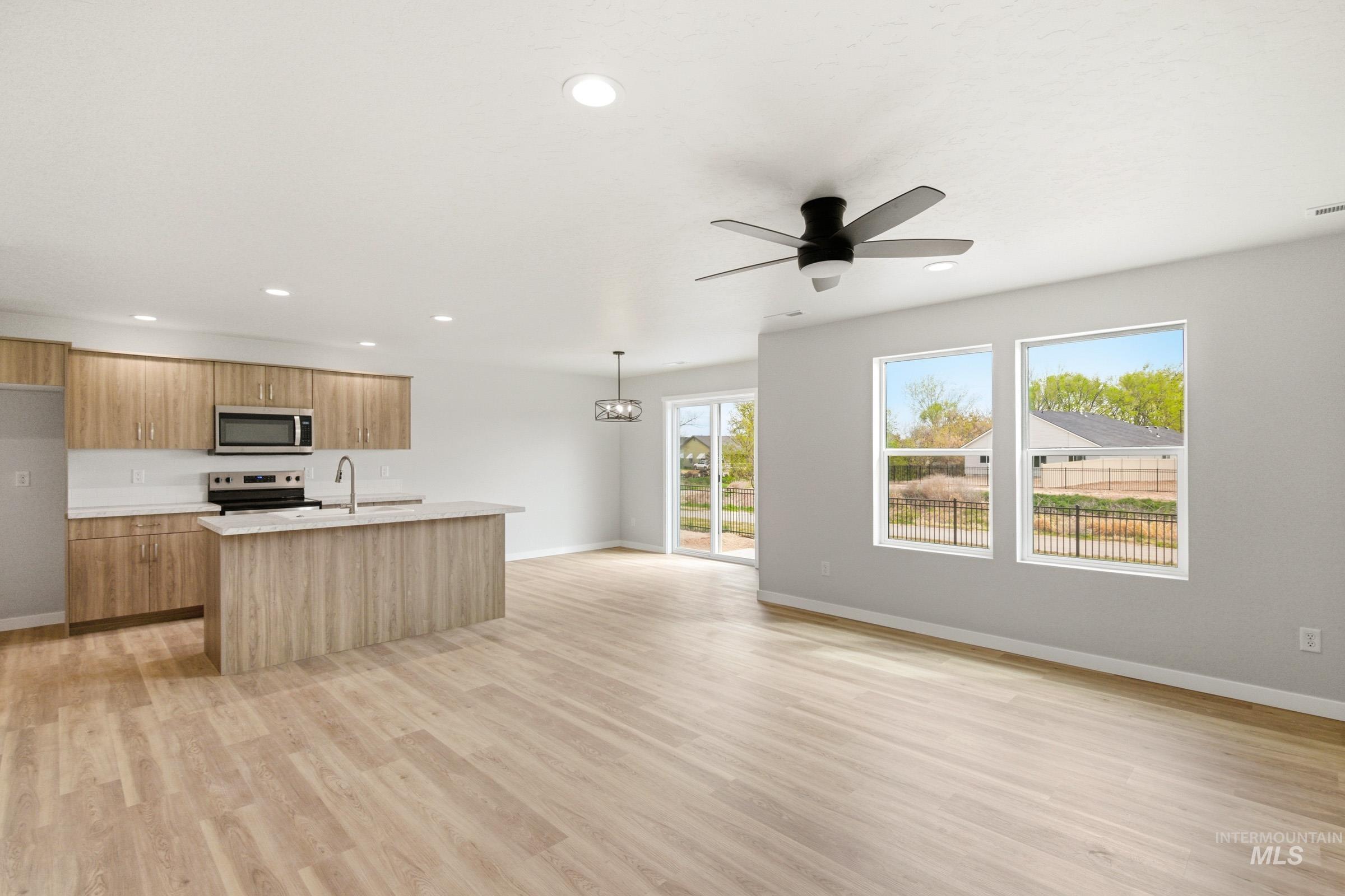 2446 West Fallon Loop Nampa, ID 83651 - Photo 18 of 19 Kitchen featuring ceiling fan, stainless steel appliances, open floor plan, light wood finished floors, and an island with sink