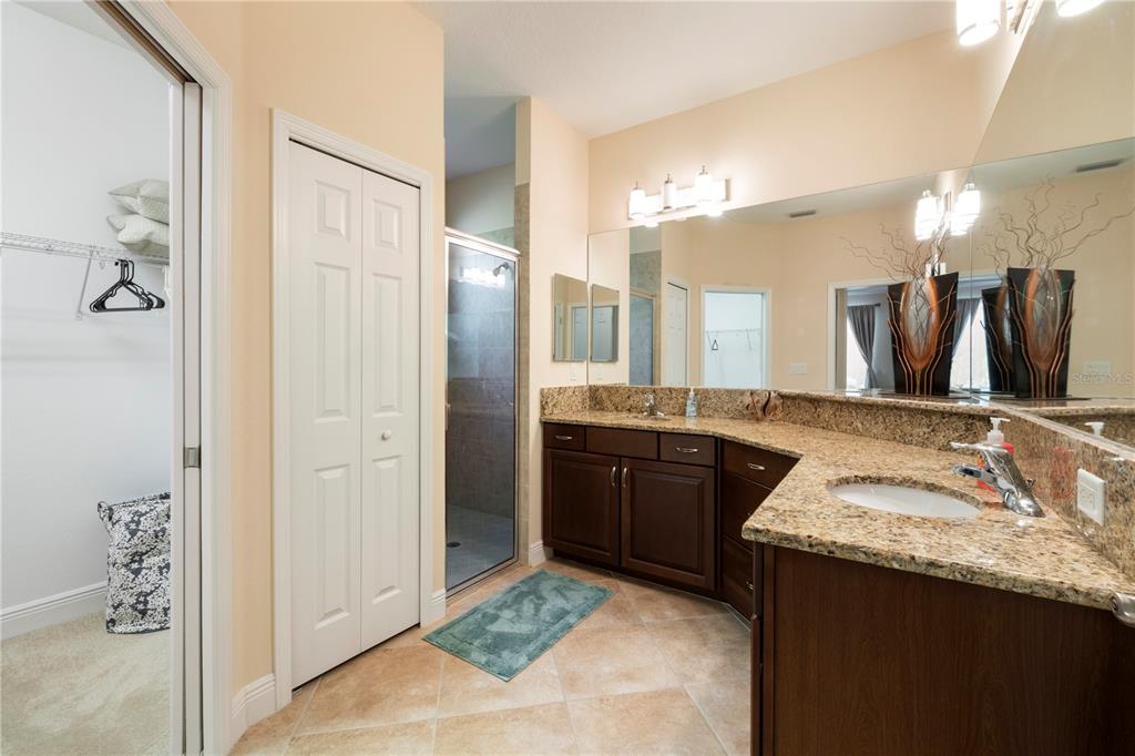 7608 Rio Bella Place Bradenton, FL 34201 - Photo 16 of 26 a bathroom with a granite countertop sink a large mirror and a shower