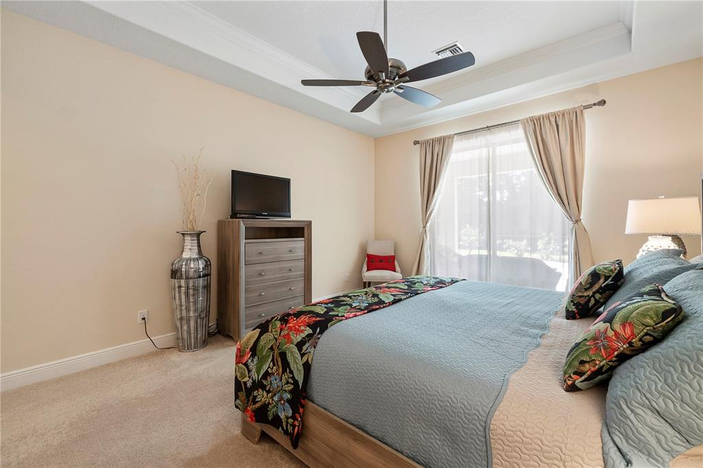 7608 Rio Bella Place Bradenton, FL 34201 - Photo 20 of 26 a bedroom with a bed and a flat tv screen on the dresser