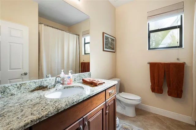 a bathroom with a granite countertop sink a toilet and mirror