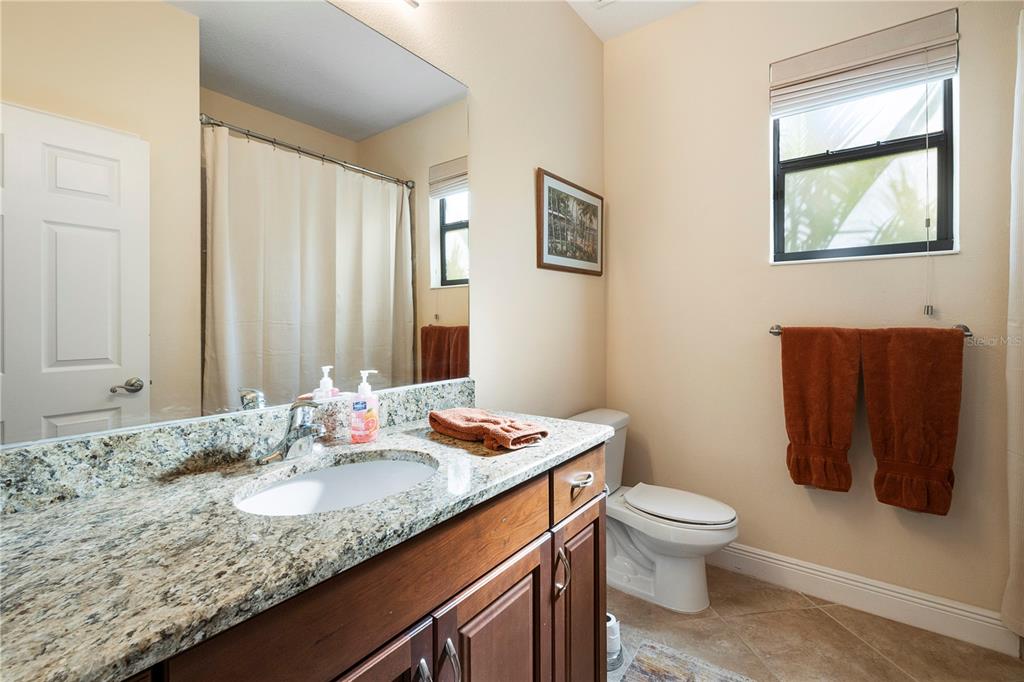 7608 Rio Bella Place Bradenton, FL 34201 - Photo 8 of 26 a bathroom with a granite countertop sink a toilet and mirror