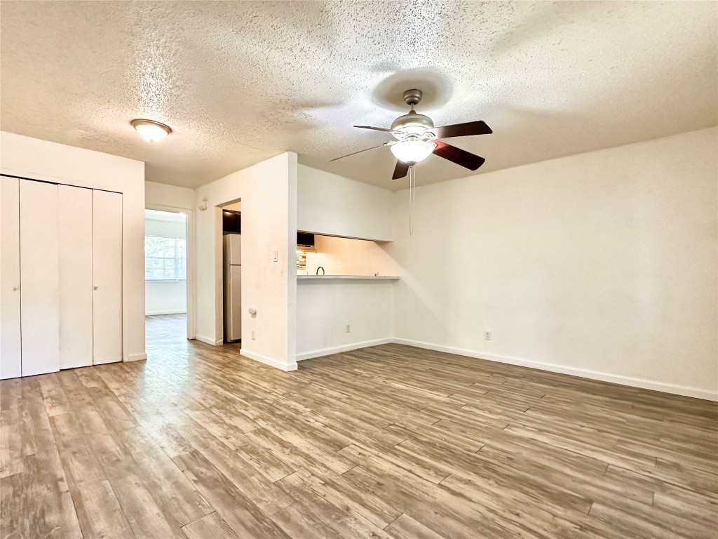 1015 Gardner Road, Unit C Austin, TX 78721 - Photo 1 of 5 Unfurnished living room featuring a textured ceiling, wood finished floors, and a ceiling fan