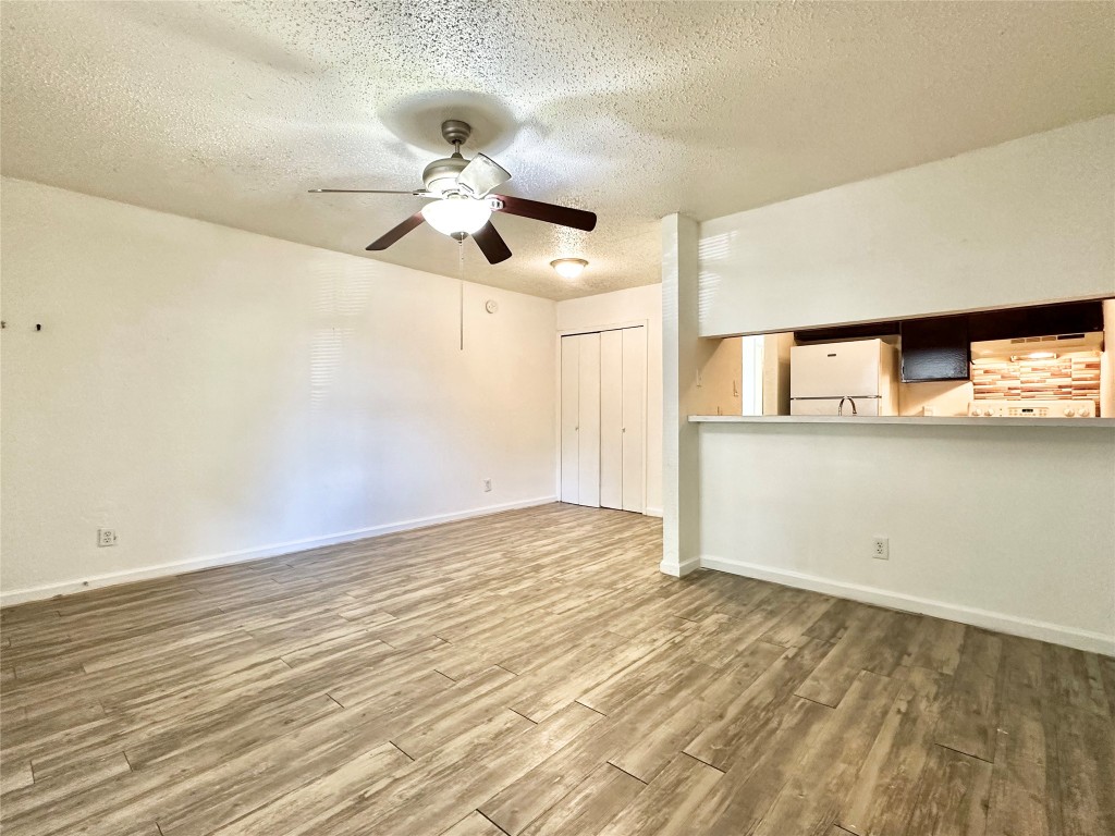 1015 Gardner Road, Unit C Austin, TX 78721 - Photo 2 of 5 Unfurnished living room with a textured ceiling, wood finished floors, and a ceiling fan
