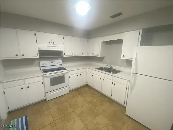 a kitchen with granite countertop white cabinets and white appliances