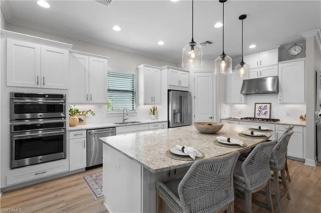 a kitchen with stainless steel appliances granite countertop a stove a sink a microwave a refrigerator and cabinets