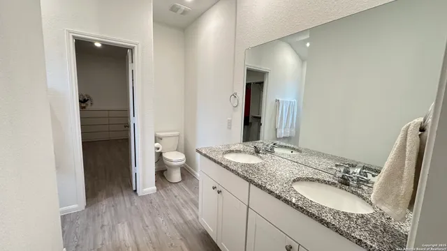 a bathroom with a granite countertop double vanity sink and a mirror