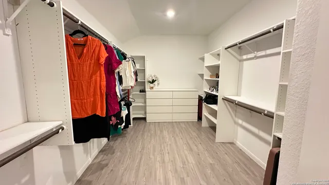a view of walk in closet with clothes and shoes