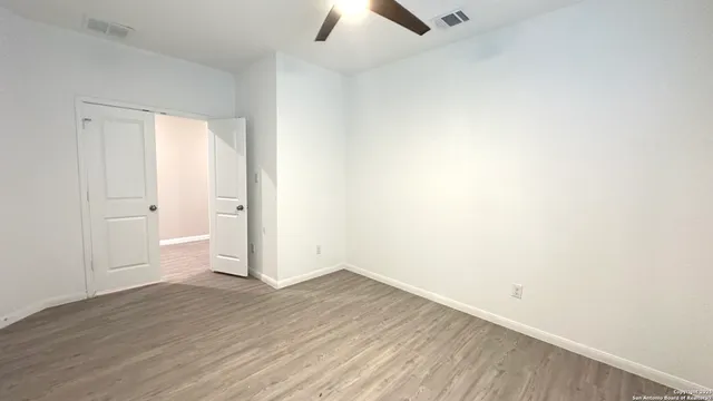 an empty room with wooden floor and ceiling fan