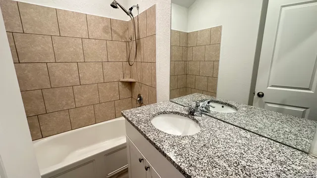 a bathroom with a granite countertop sink a mirror and shower