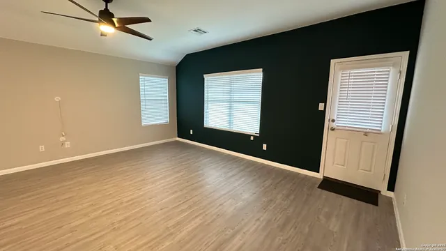 an empty room with wooden floor and windows