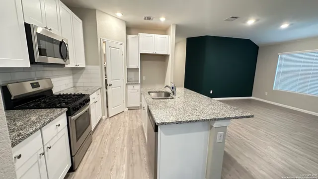 a kitchen with stainless steel appliances kitchen island granite countertop a stove a sink and a microwave