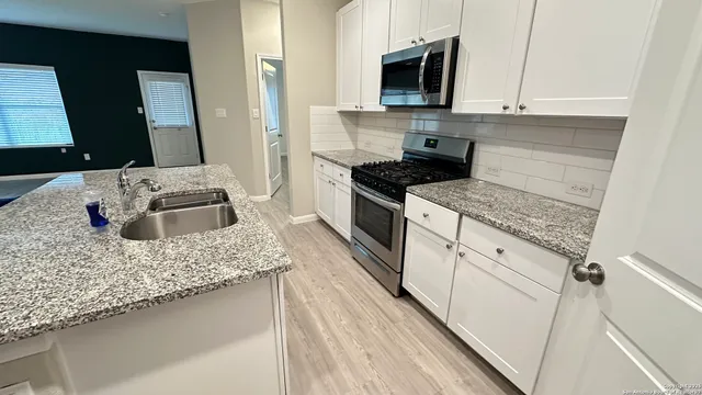 a kitchen with stainless steel appliances granite countertop a sink stove and microwave