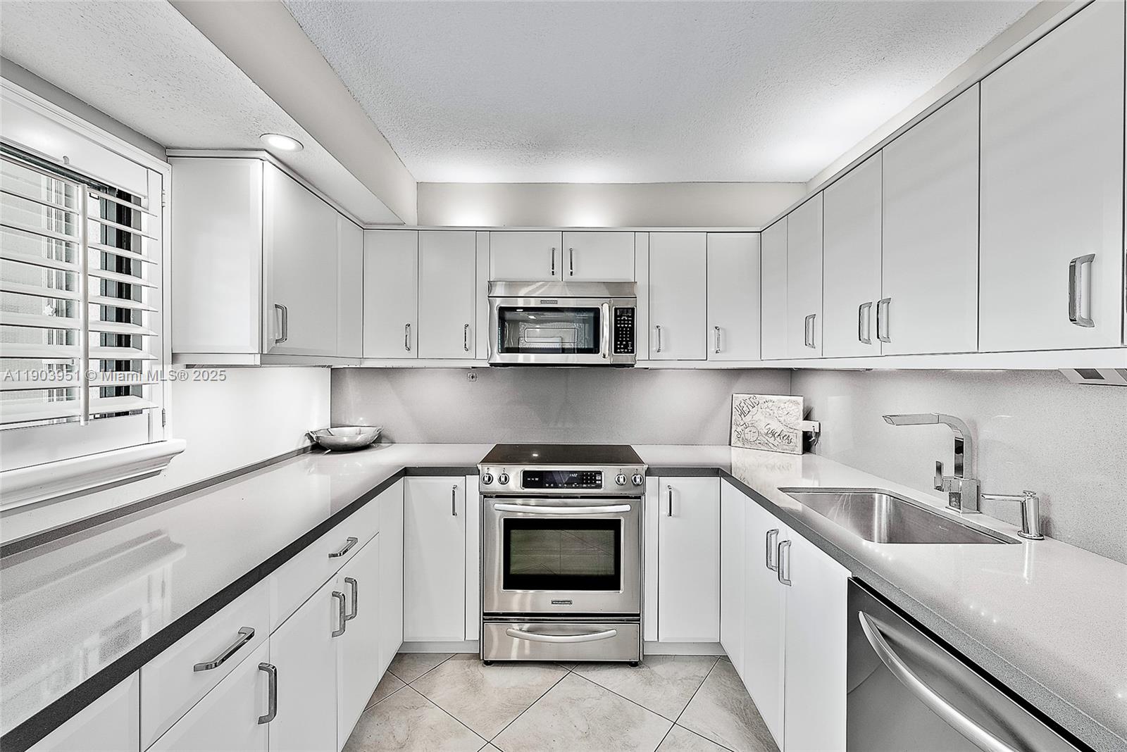 400 Ocean Trail Way, Unit 1005 Jupiter, FL 33477 - Photo 8 of 23 a kitchen with white cabinets and stainless steel appliances