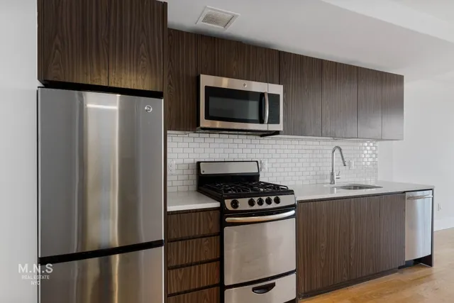 a kitchen with stainless steel appliances a refrigerator stove top oven and sink