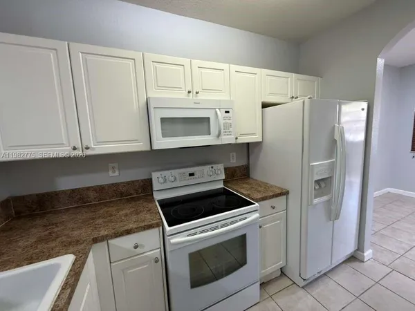 a kitchen with white cabinets and refrigerator