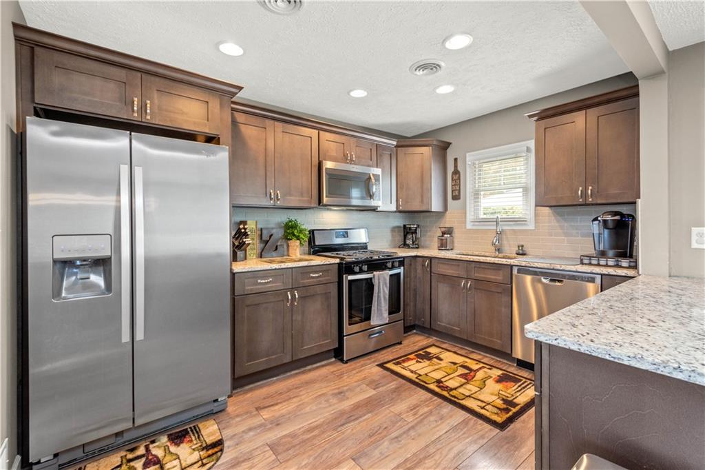 133 Baker Rd Extension Monaca, PA 15061 - Photo 10 of 25 a kitchen with stainless steel appliances granite countertop a refrigerator a stove and a sink with wooden floor