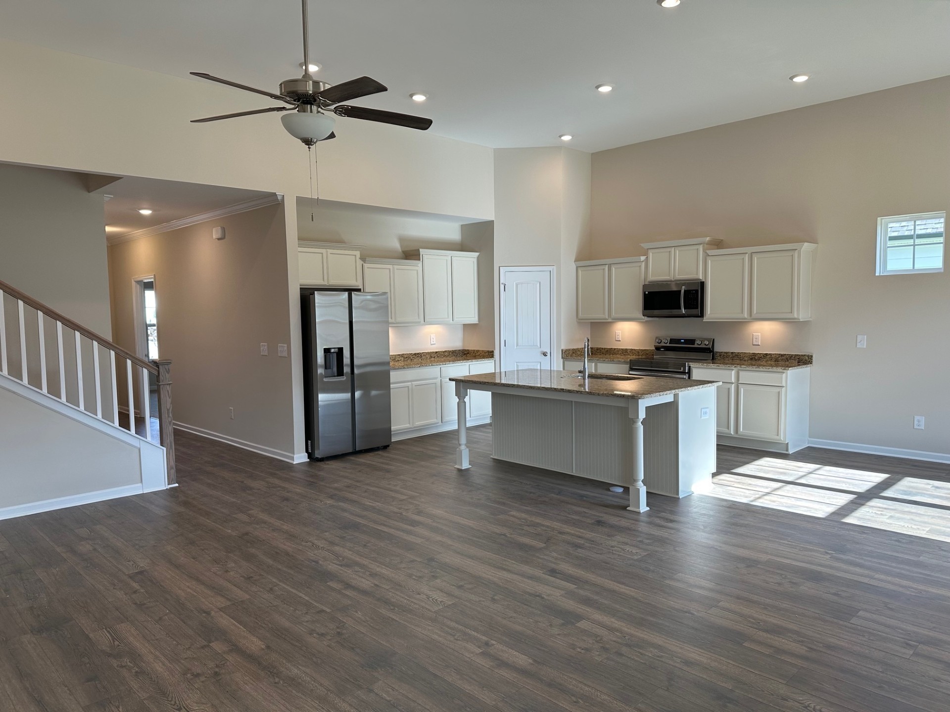 7019 Sully Court Fairview, TN 37062 - Photo 4 of 14 a large kitchen with stainless steel appliances granite countertop a stove top oven a refrigerator a sink and a dining table with wooden floor