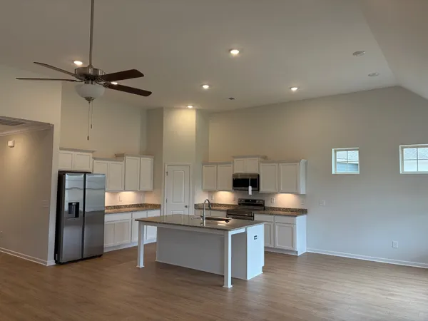 a kitchen with stainless steel appliances granite countertop a sink a refrigerator and a stove with wooden floor